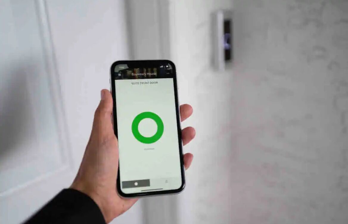 A hand holding a smartphone displaying a hotel room interface with a green loading circle.