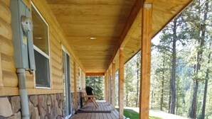 Eine überdachte Holzterrasse mit Steinwänden und Blick auf einen Wald.