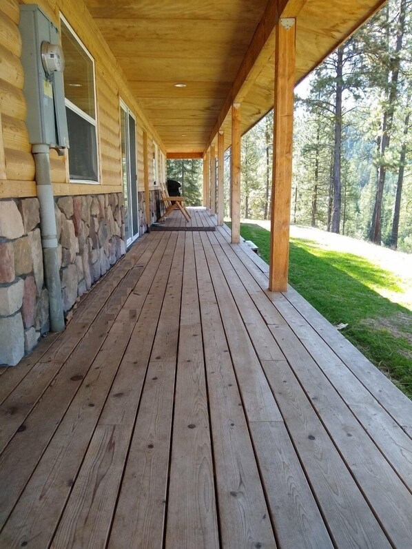 Una terrazza in legno coperta con pareti in pietra e vista su una foresta.