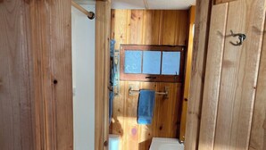 Een houten interieur met een witte wasmachine, een raam met decoratief glas en een rug met een patroon.