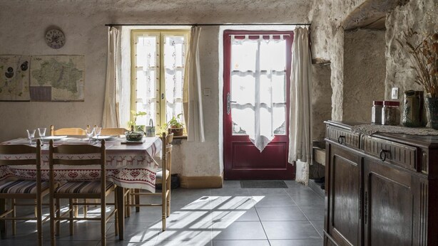 Ein rustikales Esszimmer mit Holzbalkendecke, einer roter Tür und einer Karte an der Wand.