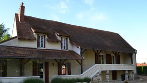 Ein zweistöckiges Haus mit steiler Dachneigung, großen Fenstern und einer überdachten Veranda.