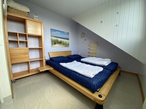 Una camera da letto con un letto, una scaffalatura in legno e un quadro appeso al muro.