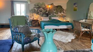 A cozy bedroom with a bed, a chair, a desk, and a large wall mural. - Country house with enclosed garden - Pets welcome (Barrais-Bussolles)