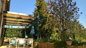 An outdoor patio with a pergola, a table with chairs, and a flowering tree. - Country house with enclosed garden - Pets welcome (Barrais-Bussolles)