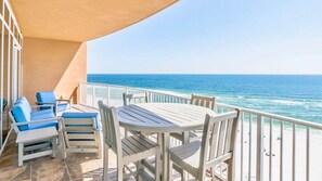 A balcony with a table and chairs, overlooking the ocean.