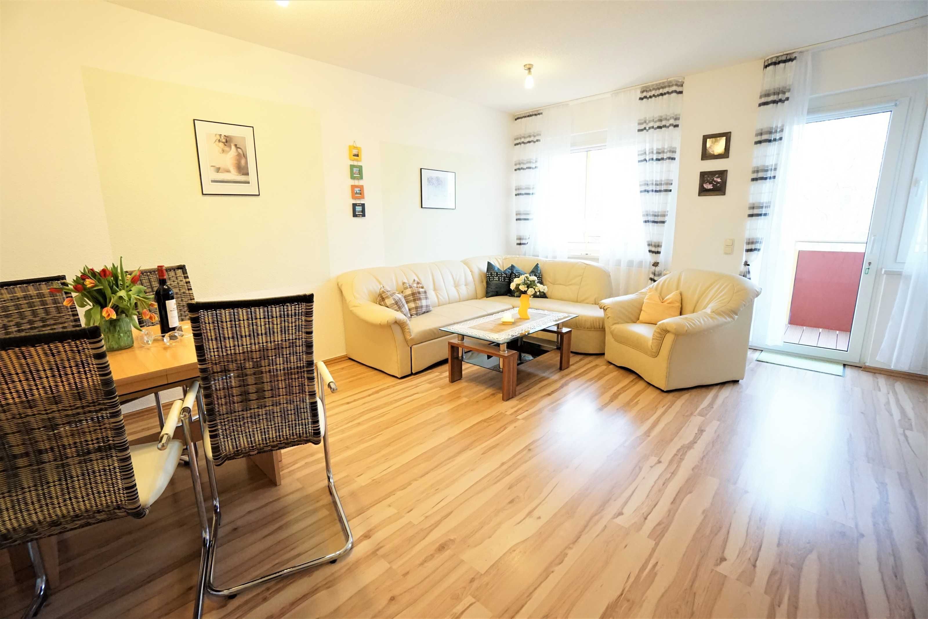A living room with a sofa, armchairs, a coffee table, and a dining area with chairs and a table.