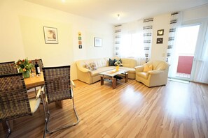 Una sala de estar con un sofá, sillones, una mesa de centro y un comedor con sillas y una mesa.