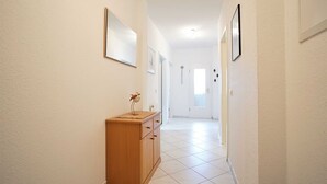 Un couloir étroit avec une armoire en bois, un miroir et une porte au fond.