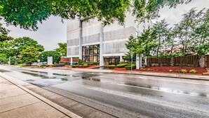 A modern building with a glass facade, a well-maintained garden, and a wet street. - Music Row Condo in Spence Manor/Guitar Shaped Pool (Nashville)