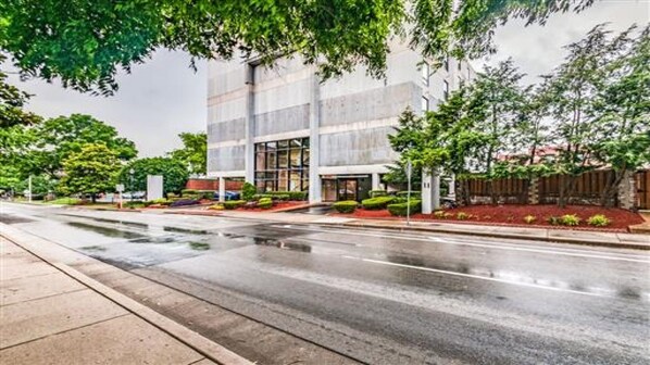 A modern building with a glass facade, a well-maintained garden, and a wet street. - Music Row Condo in Spence Manor/Guitar Shaped Pool (Nashville)