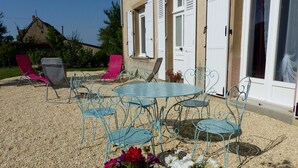 A patio with metal chairs and a table, surrounded by gravel. - Renovated countryside family cottage with garden (Cindré)