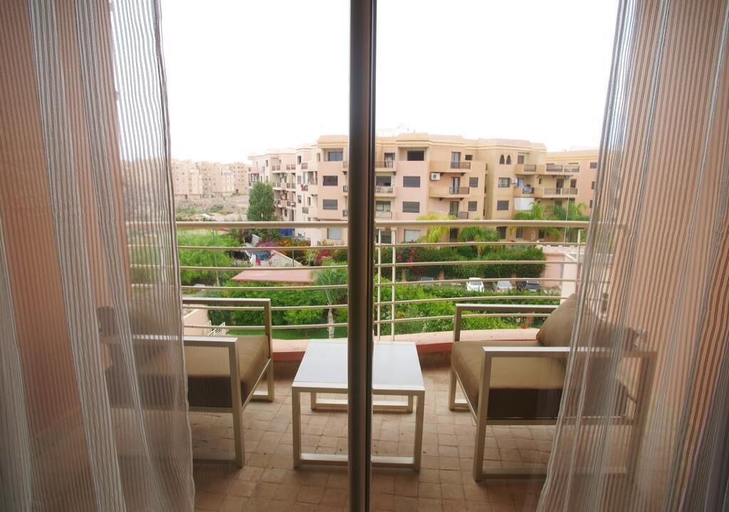 A balcony with a view of a residential area, including buildings and greenery.