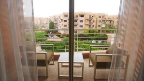 Un balcon donnant sur un quartier résidentiel, avec vue sur les immeubles et la végétation.