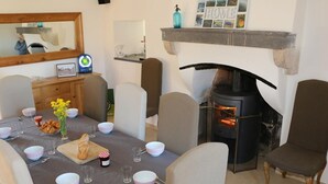 A dining room with a fireplace, a table set with bowls, glasses, and a loaf of bread. - Renovated farmhouse with private pool and pets allowed (Échassières)