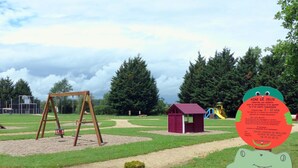 A playground with a swing set, a small red playhouse, and a green frog-shaped sign. - Cottage with AC - 4 guests (Meillard)