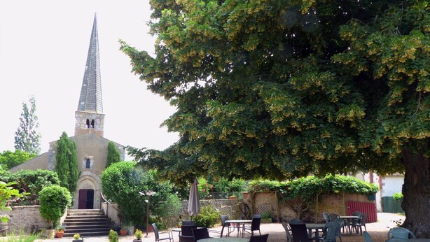 A courtyard with a church, outdoor seating, and potted plants. - Cottage with AC - 4 guests (Meillard)