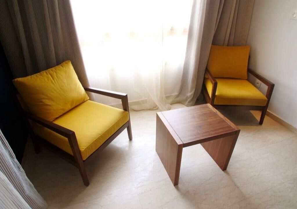 Una habitació amb dos seients grocs i una taula de centre de fusta.