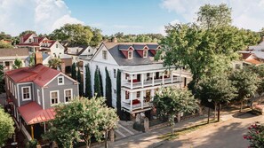 A residential area with houses featuring gabled roofs, a prominent two-story house with a balcony, and a tree-lined street. - Charleston Studio | Steps to King, Private Suite & Patio | The Charlestonian (Charleston)