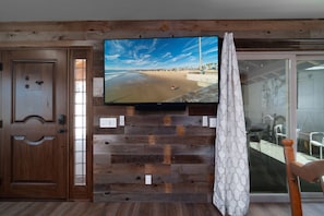 Enjoy a room with a large flat-screen TV, sliding glass door to a patio area, and a comfortable seating space.