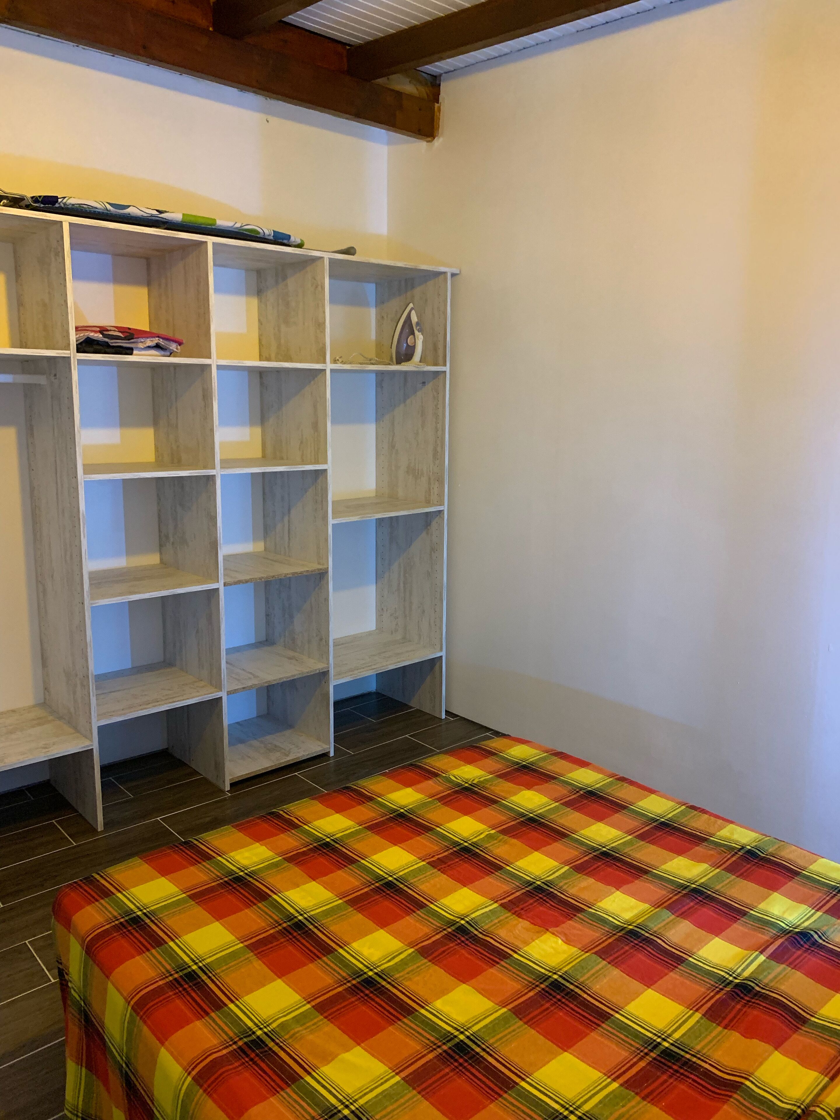Een kamer met een bed, een kledingkast en een plank.