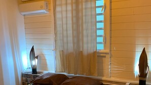 Een slaapkamer met een bed, nachtkastje, lamp en een raam met gordijnen.