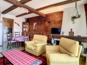 A cozy living room with wooden beams, a fireplace, a television, and comfortable seating.
