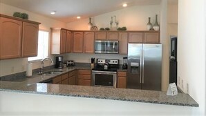 A modern kitchen with granite countertops, stainless steel appliances, and wooden cabinets. - Close to Fun, Villa In Walking distance to Lake Sumter Landing w/Golf Cart! (The Villages)