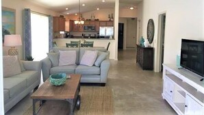 A modern living room with a sofa, coffee table, and TV stand. - Close to Fun, Villa In Walking distance to Lake Sumter Landing w/Golf Cart! (The Villages)