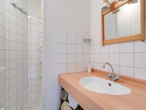 Ein Badezimmer mit einem weißen Waschbecken, einem Spiegel und einer Duschkabine.