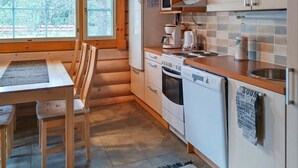 A compact kitchen with a dining area, featuring a stove, microwave, oven, dishwasher, and a small sink.