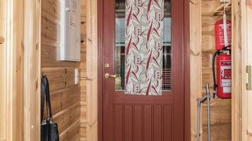 A wooden cabin with a brown door, a fire extinguisher, and a black bag hanging on the wall.