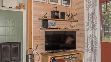 Un salon chaleureux avec une télévision, des étagères en bois et une cheminée.