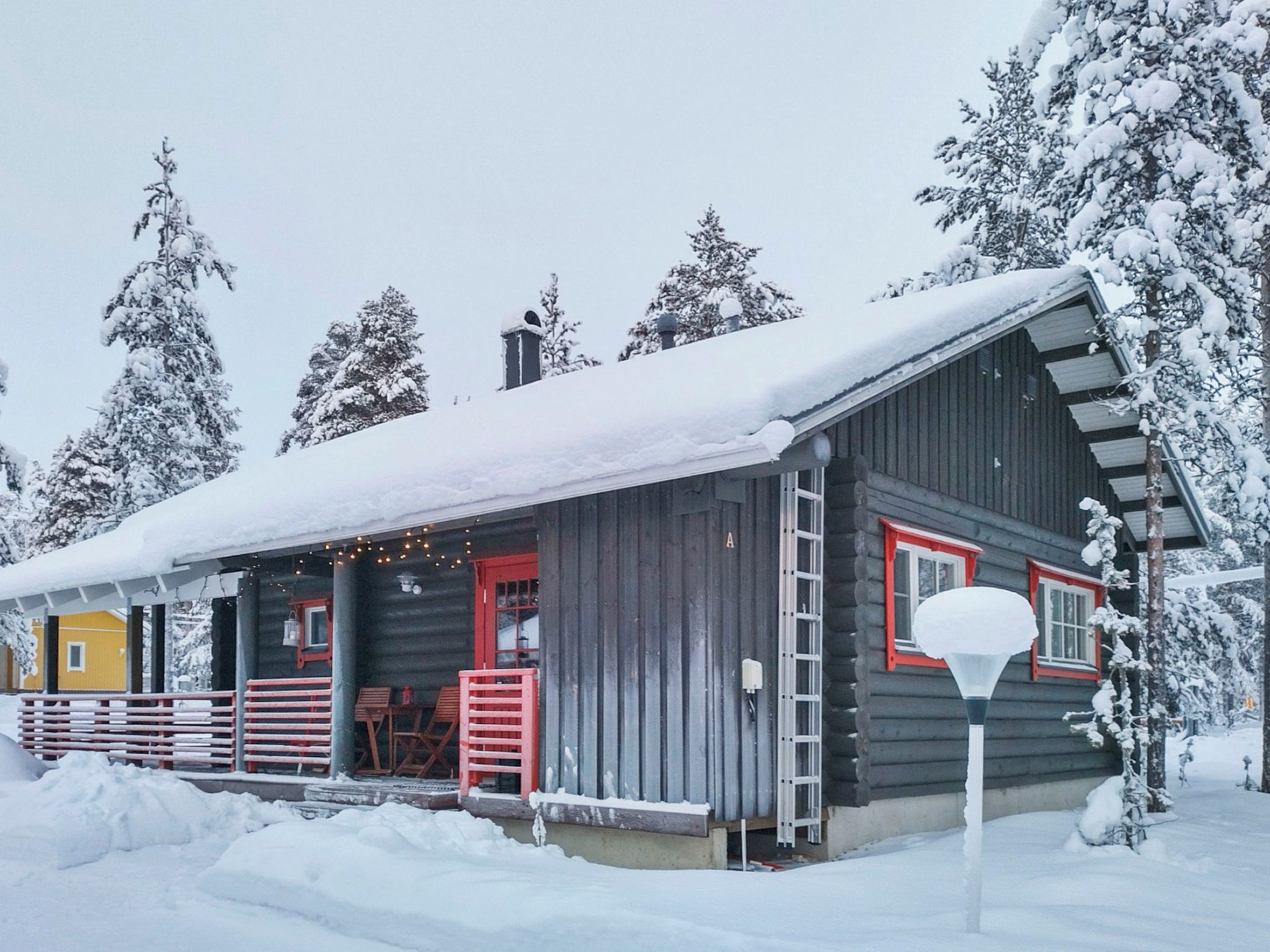 A log cabin with a porch, a red door, and a chimney.
