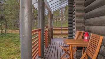 Une terrasse en bois avec une table et des chaises, une lanterne rouge et une vue sur une zone boisée.