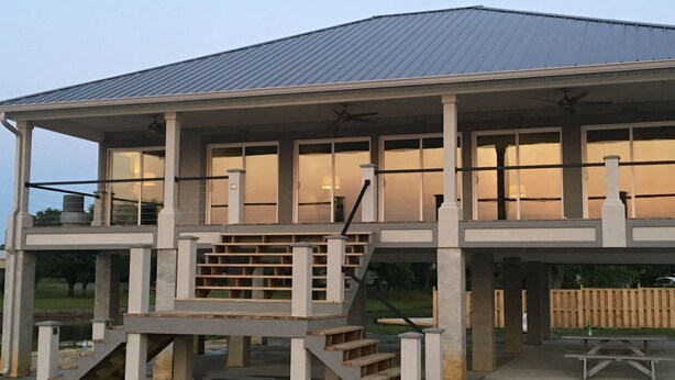 A two-story house with a covered porch, a staircase, and a picnic table. - Paradise on the lake (Centre)