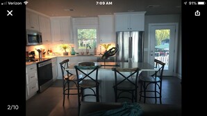 A modern kitchen with white cabinets, stainless steel appliances, and a central island with chairs. - Paradise on the lake (Centre)