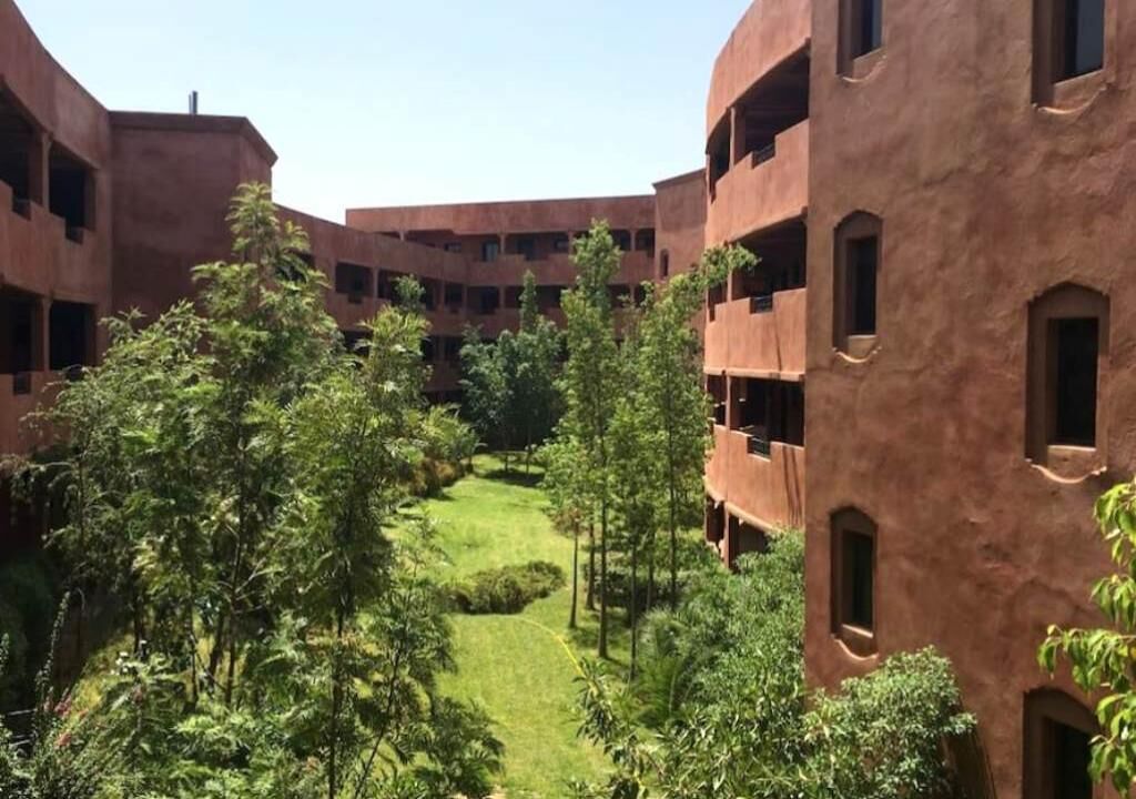Een binnentuin met meerlaags gebouwen, weelderig groen en een groot gazon.