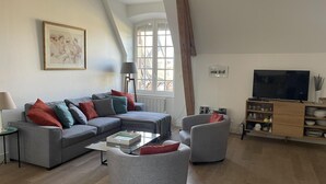 A living room with a grey sofa, a coffee table, a grey armchair, a TV, and a bookshelf. - Spacious renovated lodge near Moulins for 10 p, pets welcome, WiFi (Trévol)