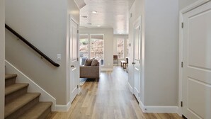 Un couloir avec un escalier sur la gauche, un canapé au centre et une porte sur la droite.