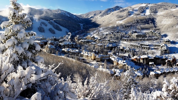 Eine verschneite Bergstadt mit mehreren Gebäuden, darunter Hotels und möglicherweise ein Skigebiet.