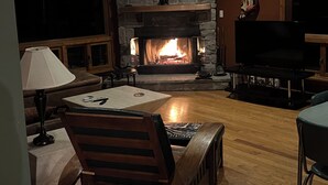 Un salon chaleureux avec une cheminée en pierre, un téléviseur et des meubles en bois.