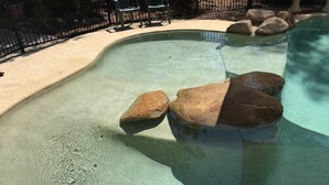 A clear swimming pool with rocks and a sandy edge. - Theme parks paradise (Ormeau)