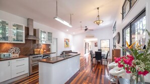 A modern kitchen with a central island, white cabinetry, and a wooden floor. - Theme parks paradise (Ormeau)