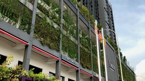 Un edificio moderno con un llamativo letrero 'EMIRA', jardines verticales y una entrada iluminada en rojo.