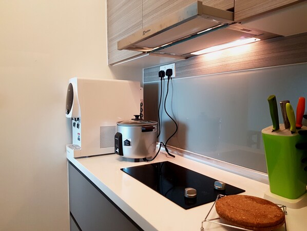 Una cocina con horno empotrado, cafetera y un portalapices verde.