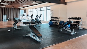 Un gimnasio con diverso equipo de ejercicio, incluyendo cintas de correr, máquinas de pesas y mancuernas.