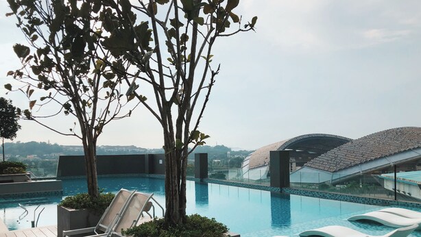 Zona de piscina en la azotea con sillones y vistas a la ciudad.