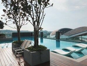 Zona de piscina en la azotea con sillones y vistas a la ciudad.