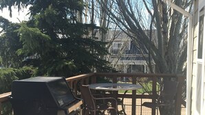 A wooden deck with a grill and chairs, surrounded by trees and a house. - Sage House- in town with LOTS of space (Ennis)